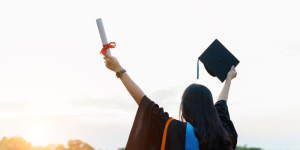 A happy graduate holding a diploma with a scenic view of Istanbul in the background.
