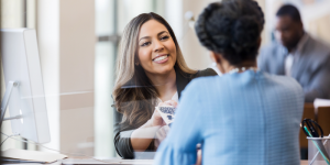 Smiling bank representative assisting a customer during account opening in a modern bank branch in Türkiye.