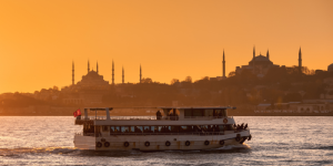 A ferry crossing the Bosphorus at sunset with Istanbul’s skyline in the background